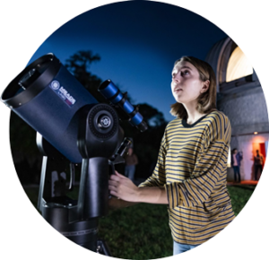 Young person uses telescope in front of UCF's Robinson Observatory