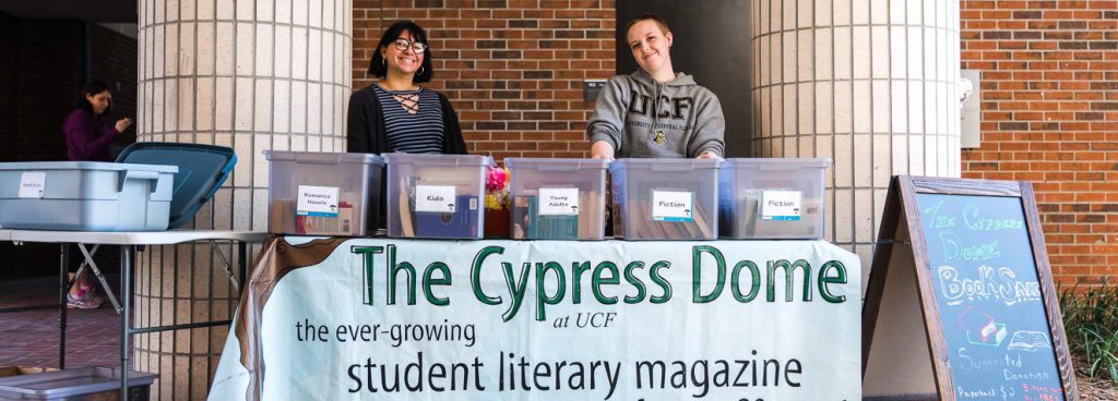 Students stand behind table during book sale