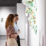 two people looking at gallery wall with green sculpture