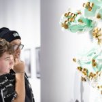 two people looking at gallery wall with green sculpture