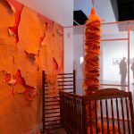 orange art installation with wallpaper and crib parts