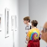 two people looking at framed art on wall