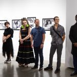 people in a line in front of wall with artwork