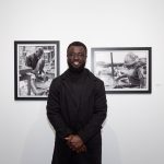 person in front of framed photos in gallery