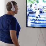 person with headphones on watching video on a tv monitor