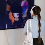 person with headphones on watching video on a tv monitor