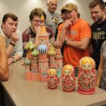 Students pose near a model of the Kremlin and nesting dolls