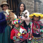 Study abroad student with Peruvian citizens in traditional attire with goats.