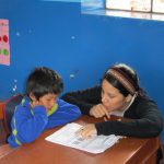 Student teaches a young child on a study abroad trip in Peru