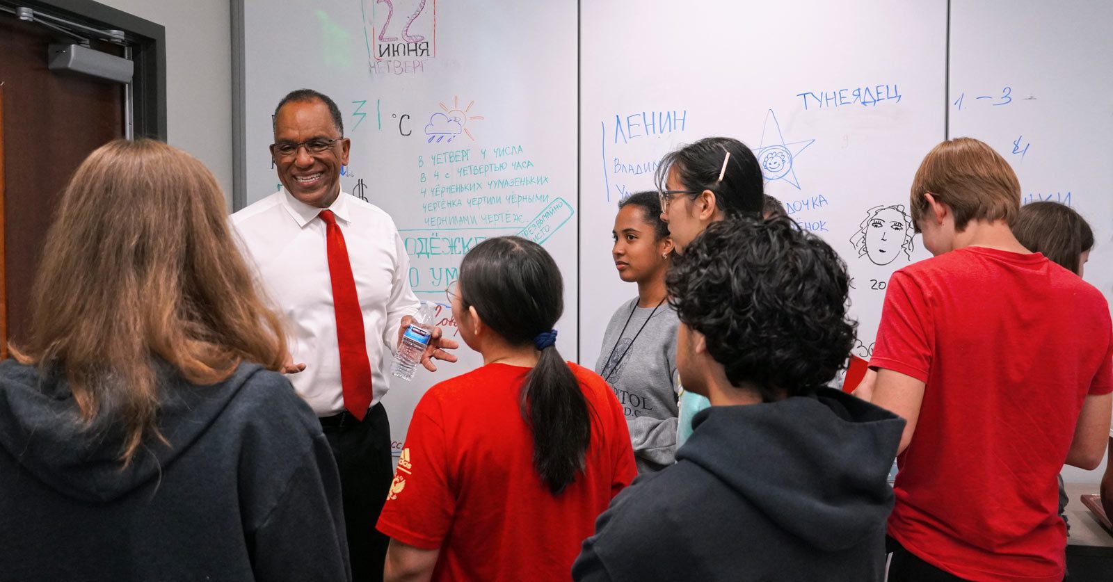 Instructor smiles and chats with a group of high school and college students