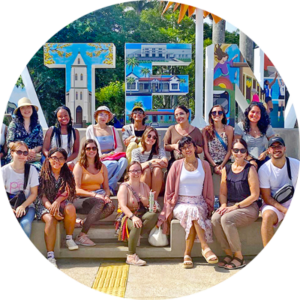 Group of students pose in front of colorful sign