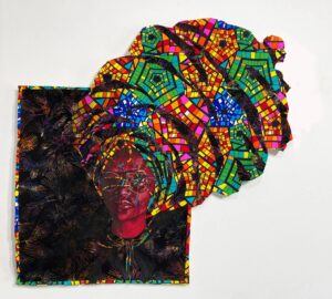 A textile artwork featuring a portrait of a person with a red-toned face, surrounded by a vibrant, mosaic-like headdress of colorful geometric patterns extending beyond the fabric’s edge.