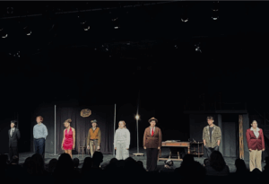 Actors in a line at the edged of a stage.