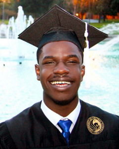 Brandon Nightingale in his UCF cap and gown in front of the reflection pond.