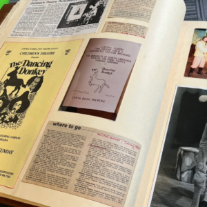 Open scrapbook page displays Children's Theatre programs for “The Dancing Donkey,” newspaper clippings, and vintage performance photos.