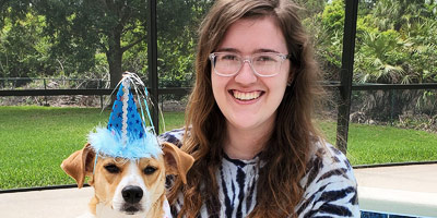 Lindsey Wright poses with a dog wearing a party hat