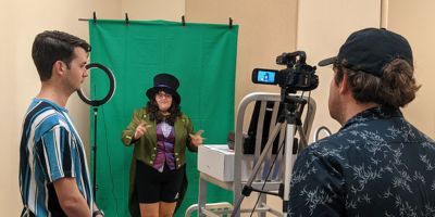 A student, dressed up as the Mad Hatter, is filmed by another student