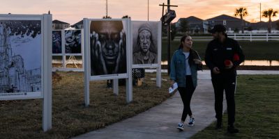 Two people walk past student artwork
