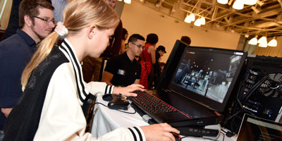 Young person tests a game on a laptop during a public event