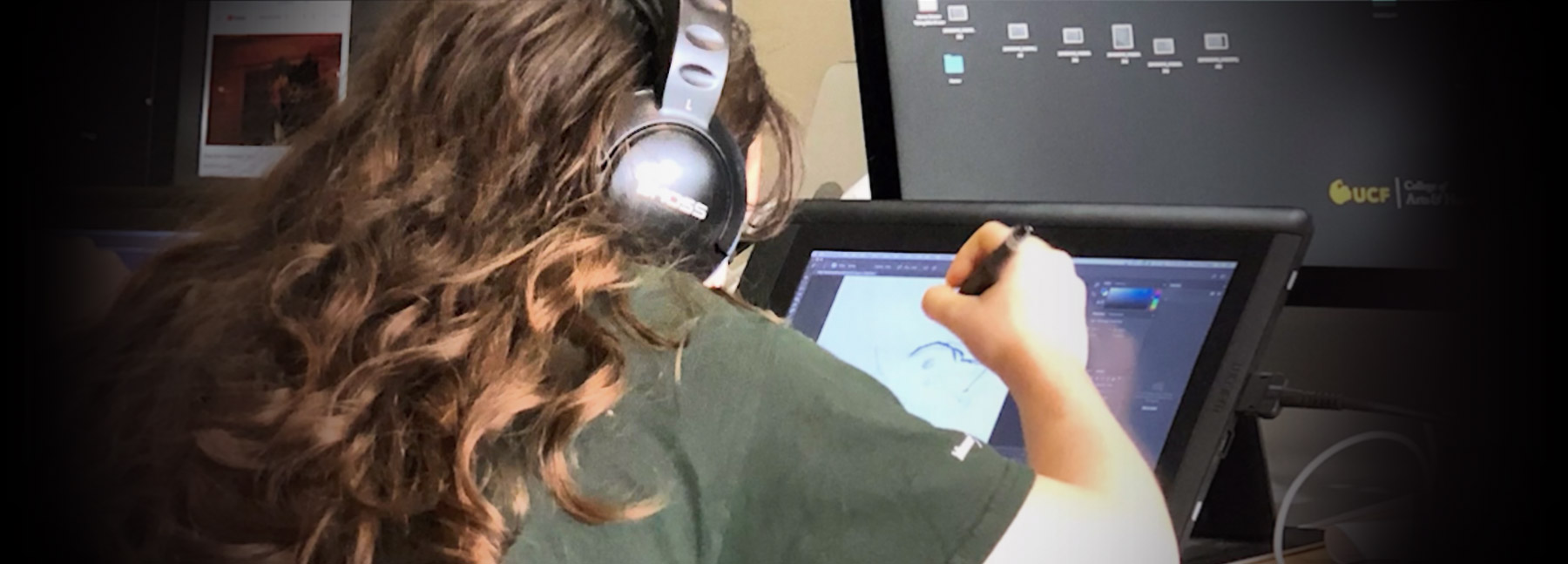 High school student with headphones draws on a tablet monitor