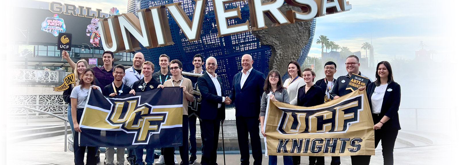 Directors and Universal Creative interns pose with UCF flags in front of Universal Studios Orlando