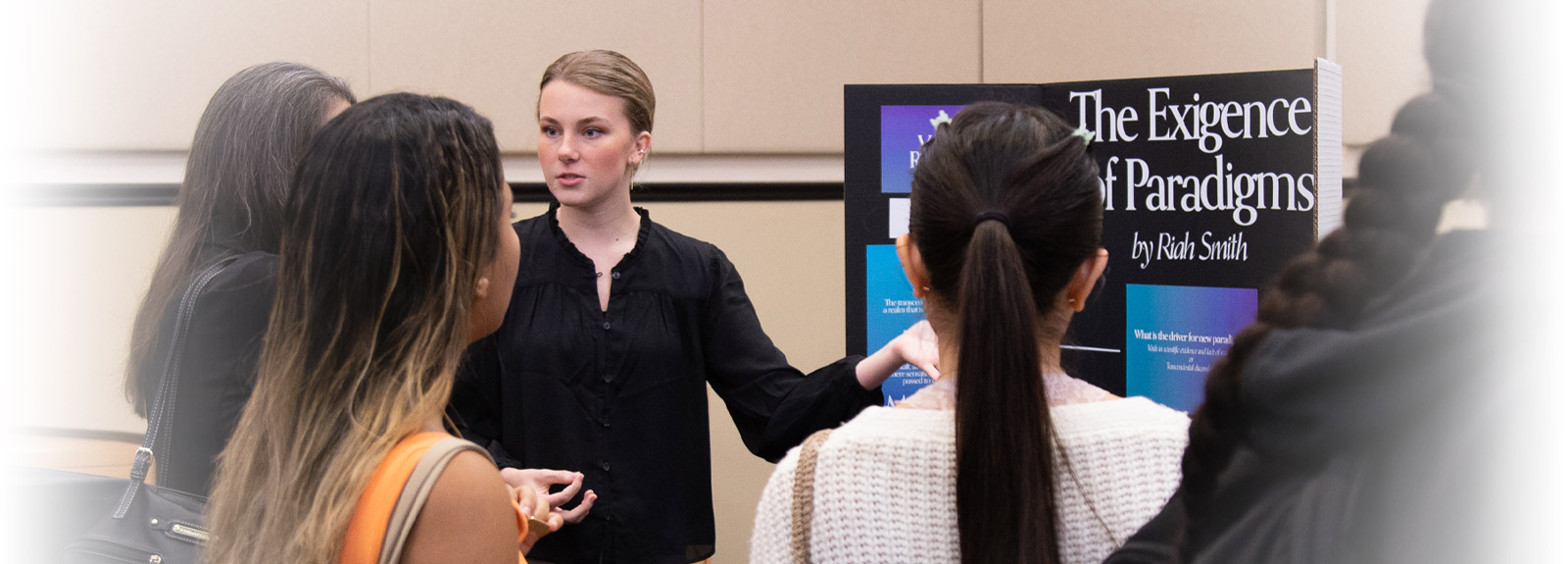 Student explains research poster to onlookers