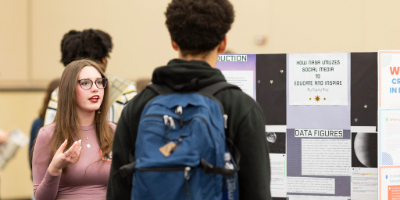 Photo of student showing off their research to another studentPhoto of student showing off their research to another student