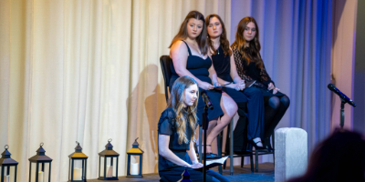 Photo of students on stage preforming theatrical monologues