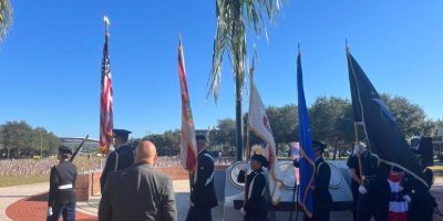 Photo of people carrying flags saluting and remembering the veteran alumni