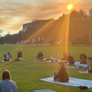 Students sitting on the grass in a circle at Memory Mall