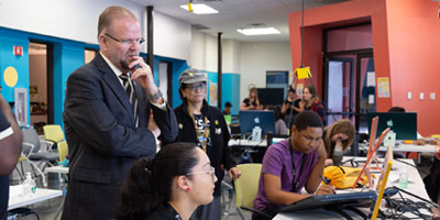 UCF president and teacher watch young students work in computer lab