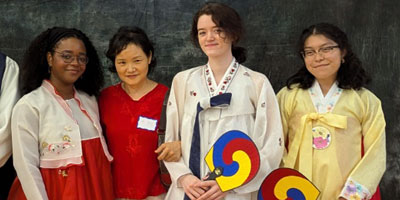 Students in traditional Korean attire pose with faculty member