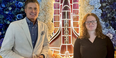 Donor poses with student in front of illuminated artwork