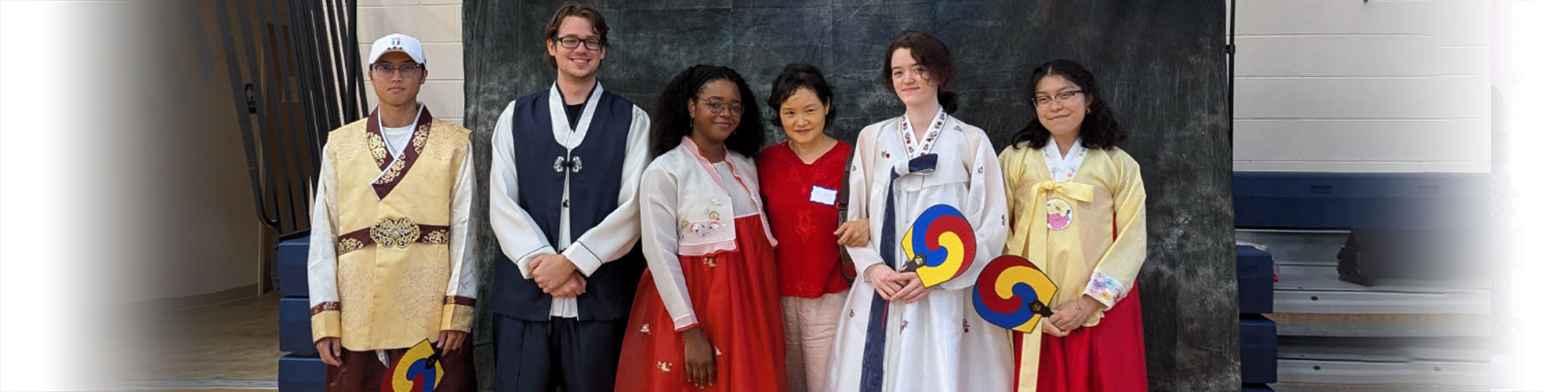 Students in traditional Korean attire pose with faculty member