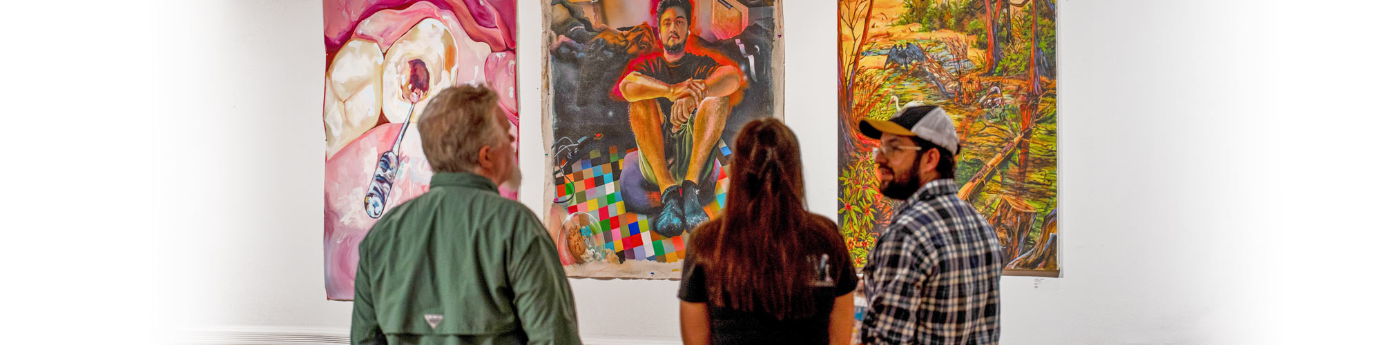 People look at paintings on gallery wall