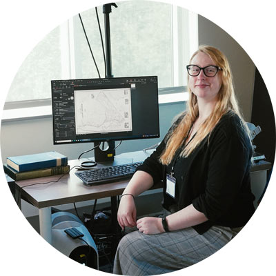 Student poses with computer used to scan an old map