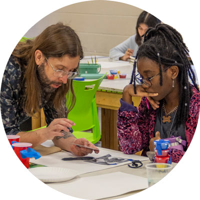 Instructor works with young artist at table