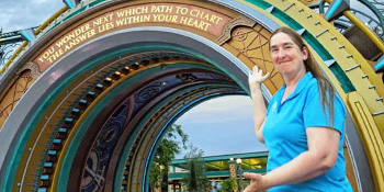 Faculty member poses in front of Epic Universe theme park gate