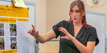 Student gestures in front of a research poster
