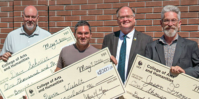 Staff award winners holding large checks pose with Dean Moore