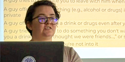 Person presents in front of a screen with text