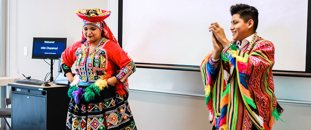 Two performers in traditional indigenous South American clothing present in a classroom