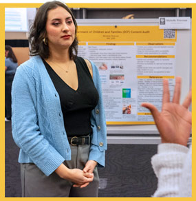 Students converse in front of a research poster