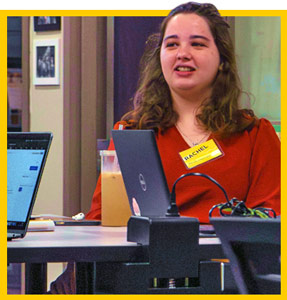 Writing tutor sits at a desk with laptops