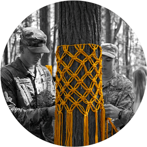 Army ROTC students decorate a tree with yellow tassels