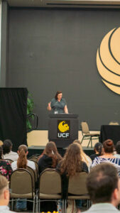 Student presents on stage with laptop and microphone