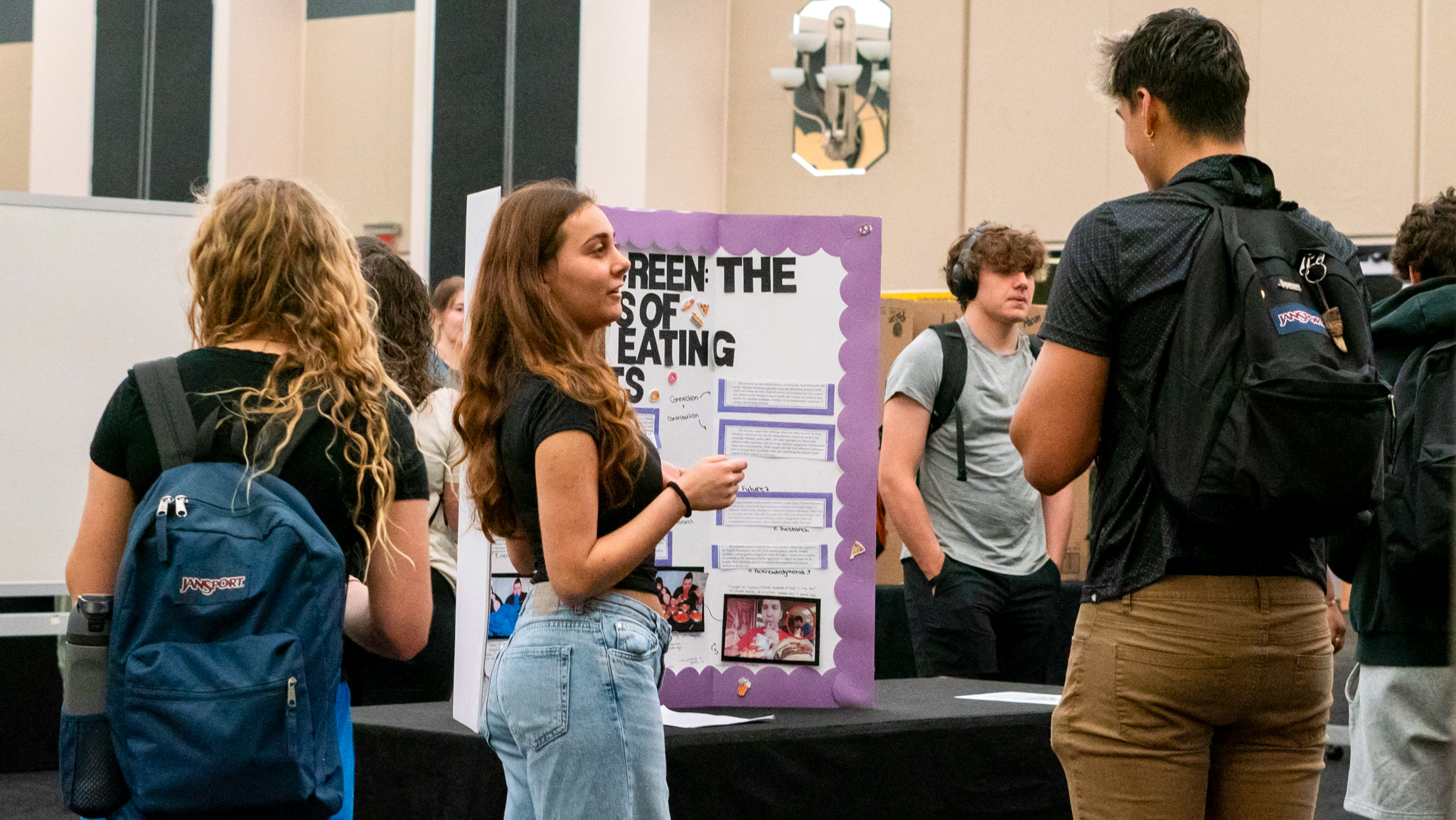 Student presents poster in front of onlookers
