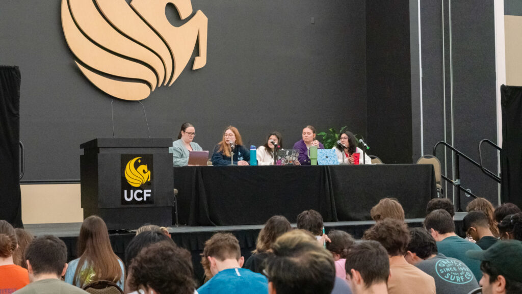 Students and other visitors gather around research posters